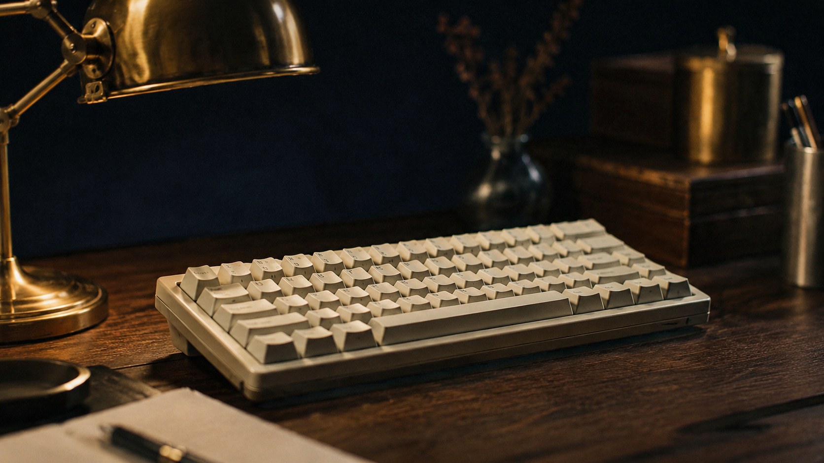 真鍮のデスクランプに照らされたアイボリーのメカニカルキーボード